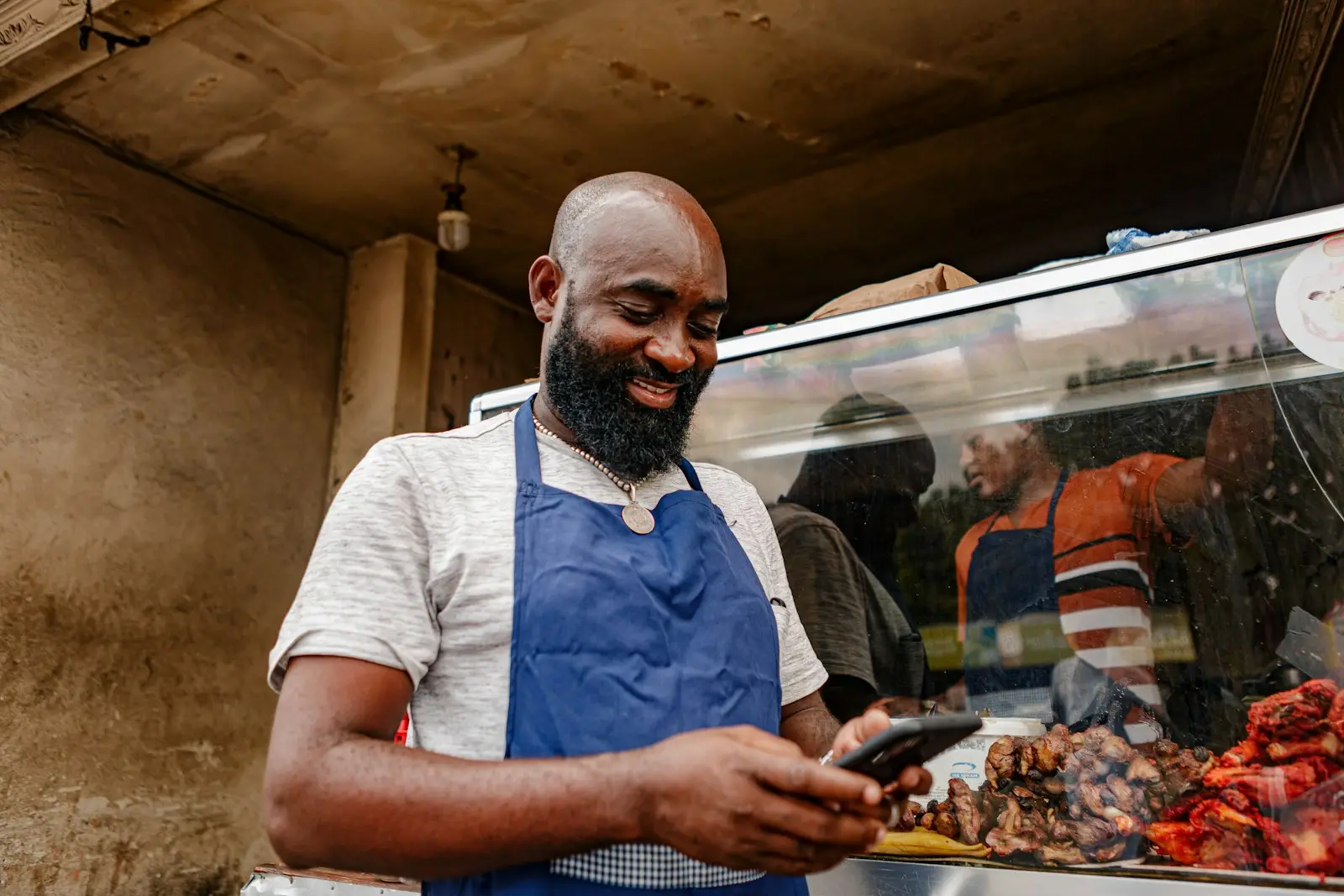 A shop owner in an apron checking an order on his phone