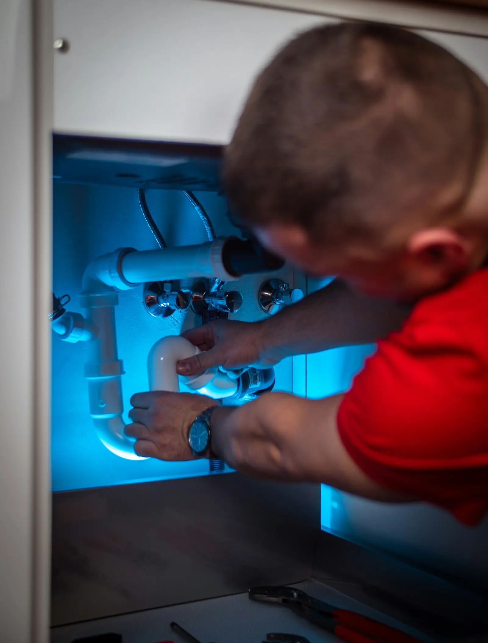 A plumber fixing the pipes under a sink