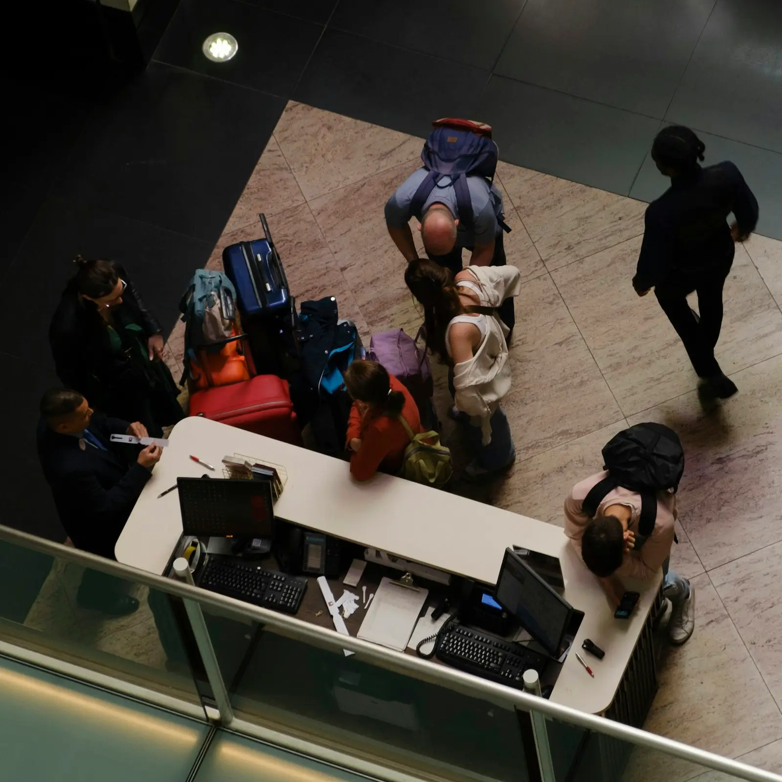 Guests with their luggage checking in at a hotel front desk, seen from above
